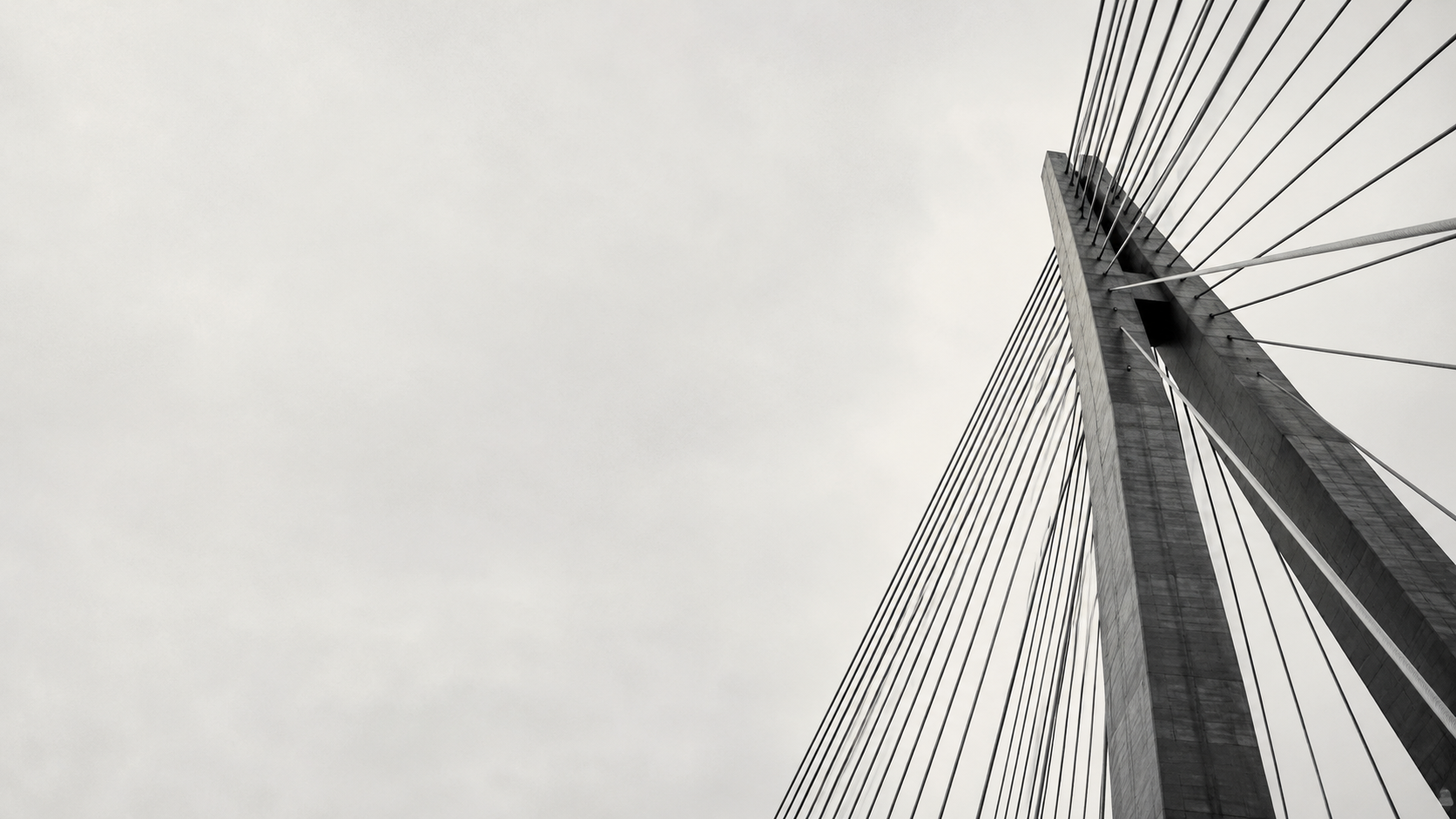 Concrete bridge pylon with radiating cables against a pale sky